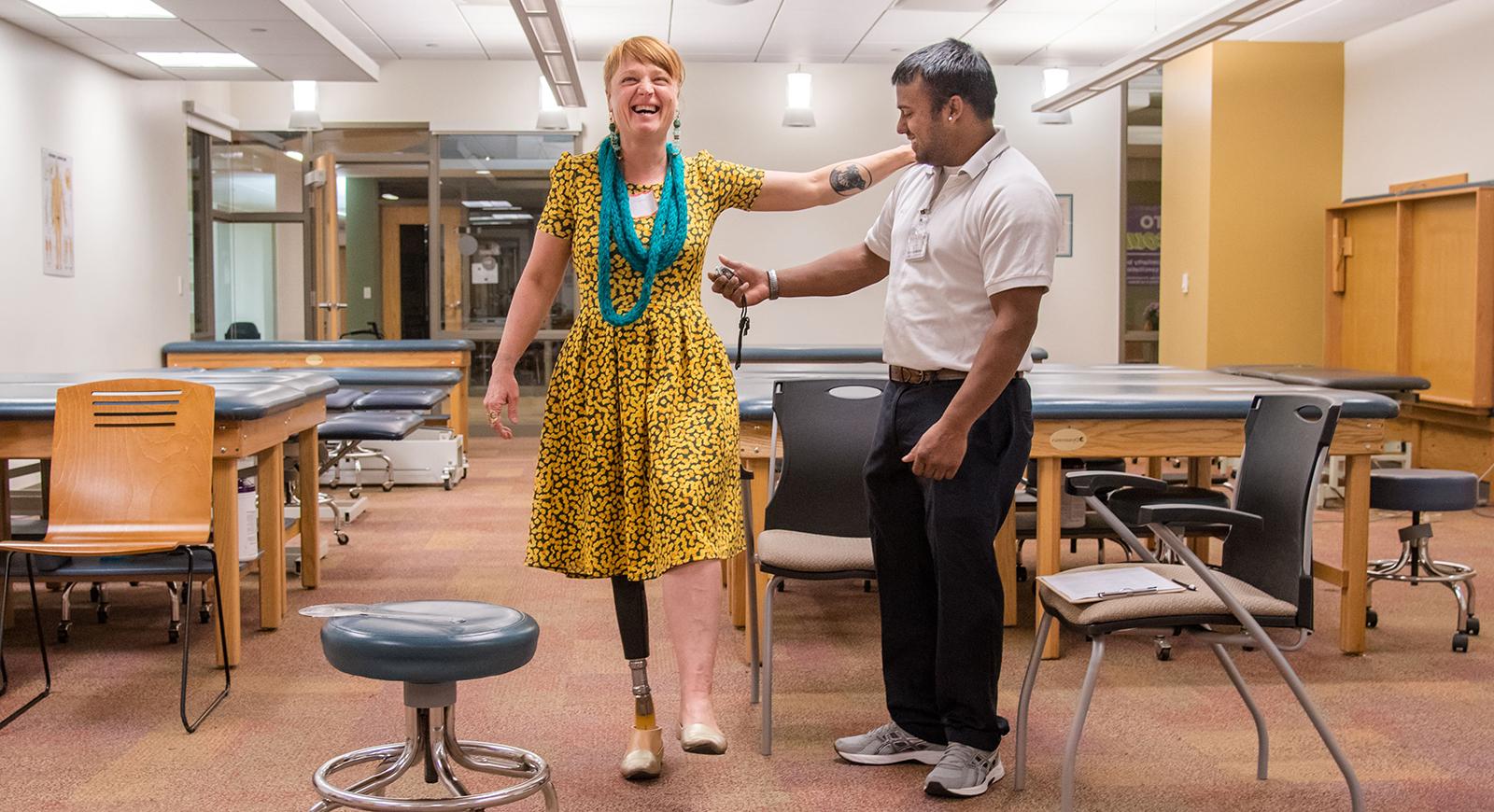 一位理疗专业的学生正在帮助一位装有义肢的妇女